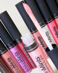 Collection of Boston Mints lip glosses with black caps on a light background