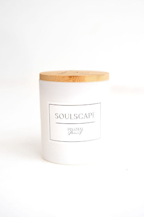 A white candle with a wooden lid and a label that reads 'SoulScape'. The candle is placed against a white background.