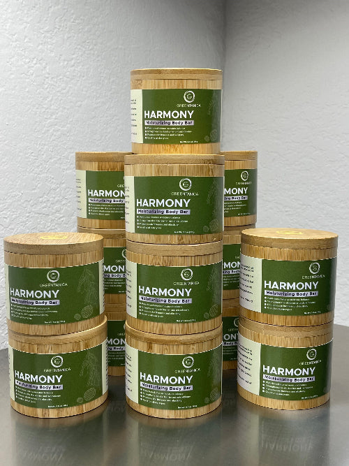 Stack of Harmony body bar containers on a reflective surface with a neutral background