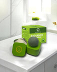Green facial serum packaging on a bathroom counter with a box labeled 'Radiance Serum'.