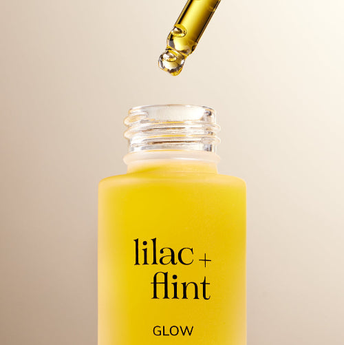 Yellow bottle of 'lilac + flint' with dropper on beige background