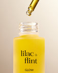 Yellow bottle of 'lilac + flint' with dropper on beige background