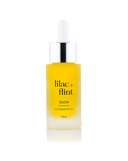 Yellow bottle of lilac + flint Glow Microbiome Oil on a white background