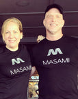 Two people wearing black 'MASAMI' t-shirts in an indoor setting.