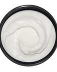 Top view of a container with white cream on a dark green background