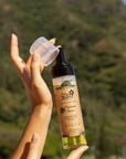 Hand holding a bottle of Australian Cypress essential oil with a scenic background