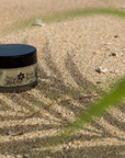 Jar of cream on sand with a blurred background