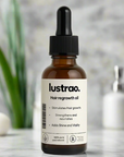 A bottle of lustrao. Hair regrowth oil with a black dropper cap and white label, set against a softly blurred bathroom background with a plant and soap dispenser.
