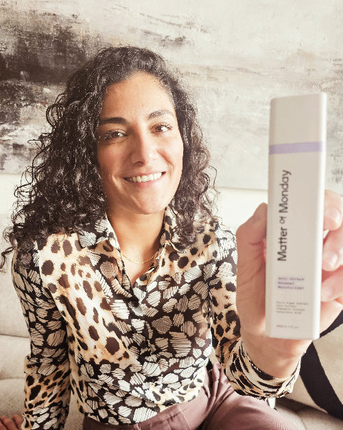 Woman holding a 'Matter of Monday' product against a rustic wooden background