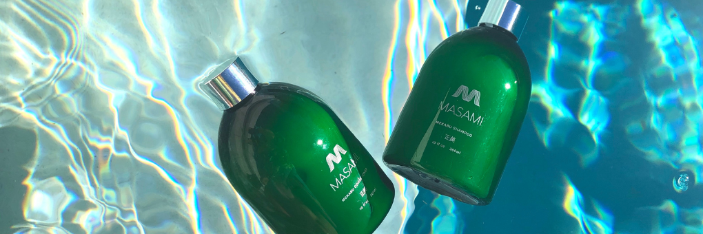 Two green bottles with silver caps on a reflective water surface