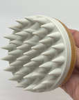 White scalp scrubber in hand