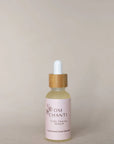 Bottle of Om Chanti serum with dropper on a beige background