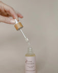 Bottle of 'La Om Chanti' serum with dropper on a beige background