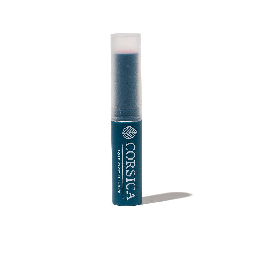 A stick of Corsica Scents lip balm with a subtle pink tint, labeled 'ROSE GLOW LIP BALM'.