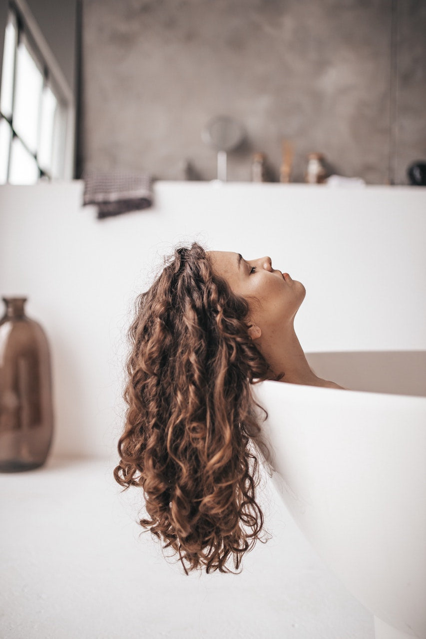 Girl with beautiful curly hair in bathtub