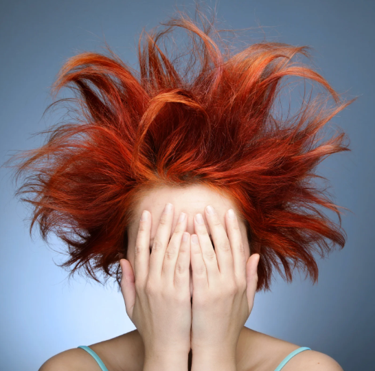 Woman covering her face with crazy hair