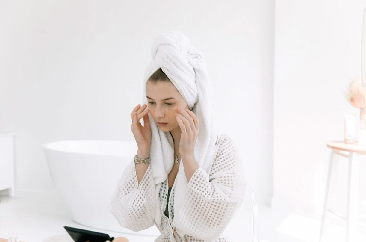 Woman in robe and towel applying skin care