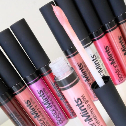 Collection of Boston Mints lip glosses with black caps on a light background