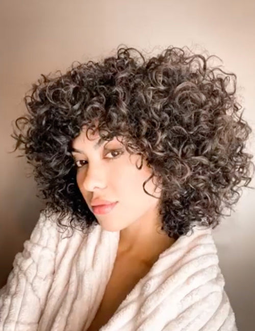 Woman with curly hair wearing a white scarf against a neutral background