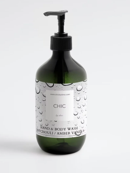 A dark green translucent pump bottle of hand and body wash with a black pump dispenser and a white label featuring a water droplet pattern. The label reads 'CHIC by DMO' and 'HAND &amp; BODY WASH' with 'BATCHOULI / AMBER VANILLA' below.