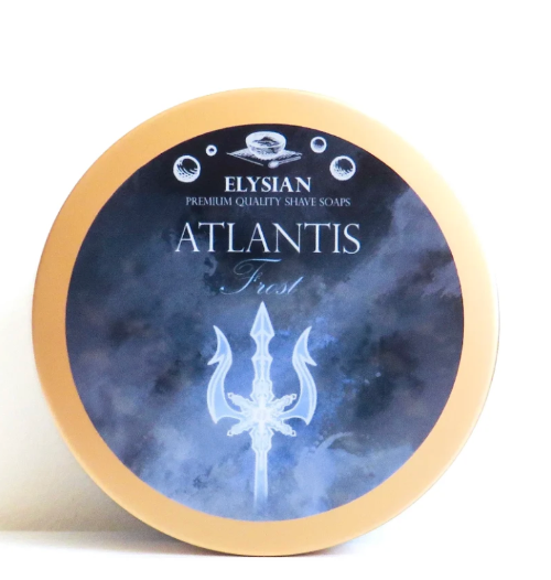 A round tin of Elysian Atlantis Fresh shave soap, featuring a navy blue and light blue watercolor-style label with a white trident graphic and a gold-colored rim, set against a plain white background.