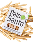 A box of Palo Santo sticks surrounded by scattered natural wood incense sticks on a plain white background.
