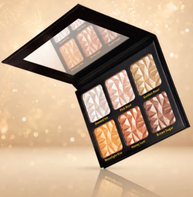 An open six-pan makeup highlighter palette with a black case, displayed against a warm, sparkling gold background. The pans are labeled 'Aventus Ice', 'Pink Rose', 'Golden Hour', 'Moonlight Kiss', 'Honey Lux', and 'Brown Sugar'.