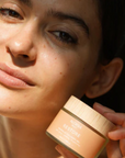 Woman holding a skincare product with a blurred background