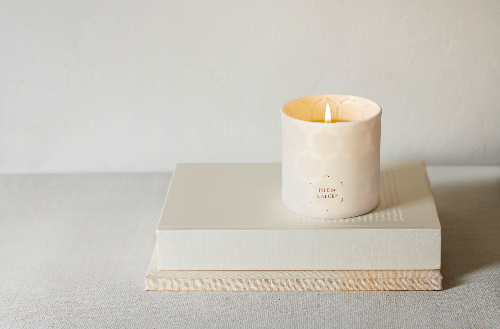 A lit beeswax candle placed on top of a closed book, with the candlelight illuminating the page.