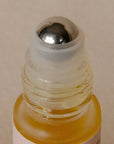Close-up of a small glass bottle with a metal cap on a beige background