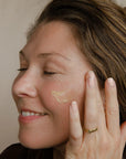 Woman applying cream to her face with a neutral background