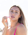 Woman holding a pink lip balm against a white background