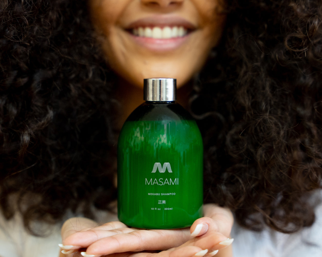 Woman with curly hair holding MASAMI shampoo